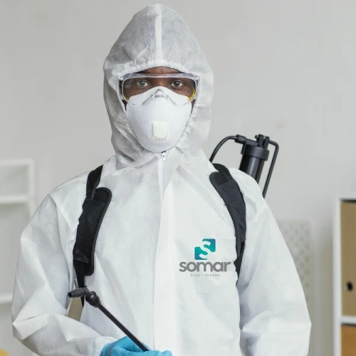 Técnico da Somar Dedetizadora com traje de proteção completo, máscara, óculos e pulverizador costal